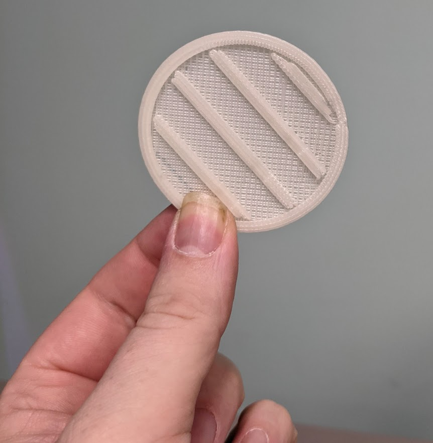 a close up photo of a thin 3D printed circle with stripes, the raft