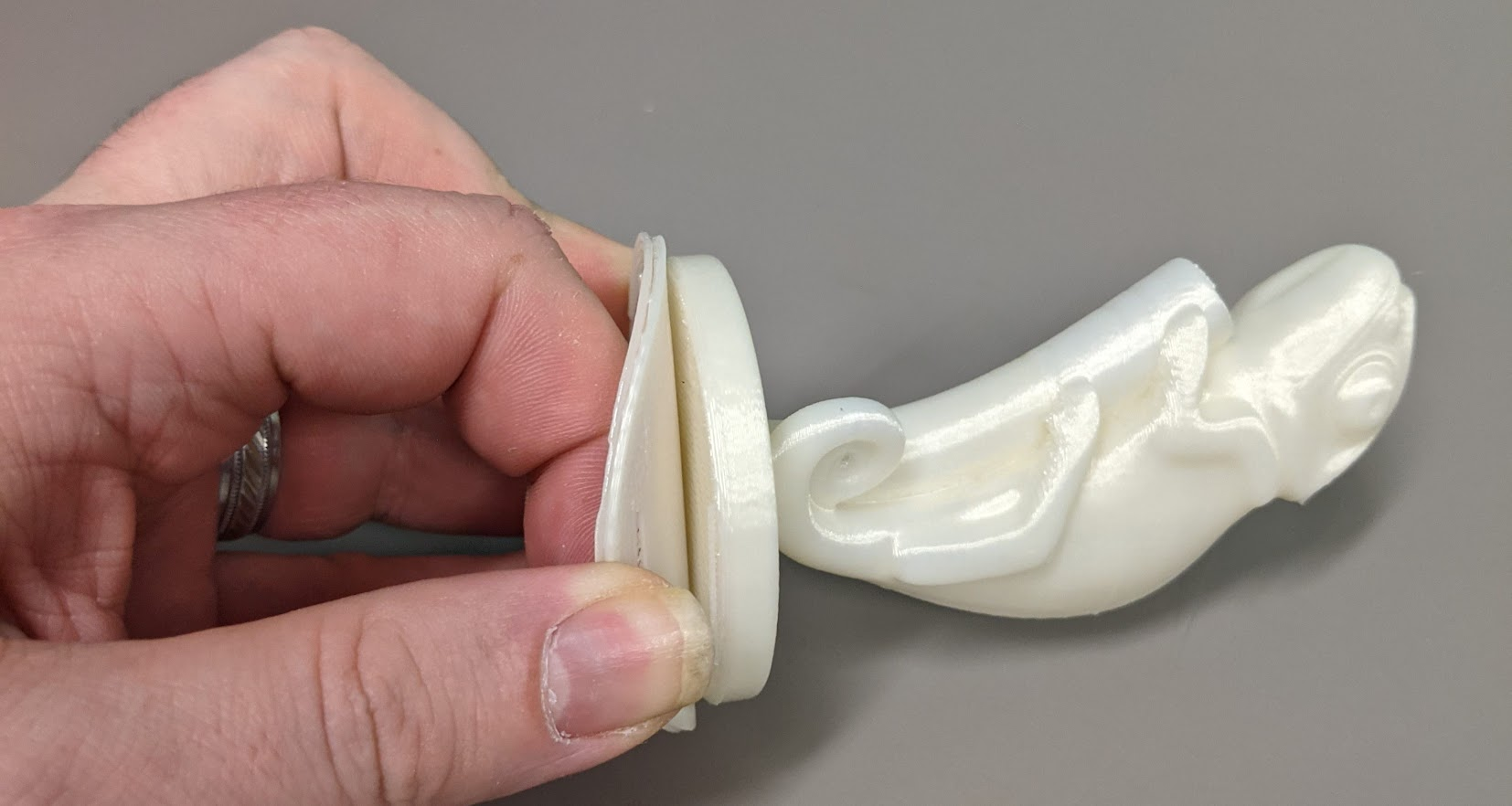 A thin layer of 3D printed material, the raft, being peeled away from the chameleon pen holder 3D print