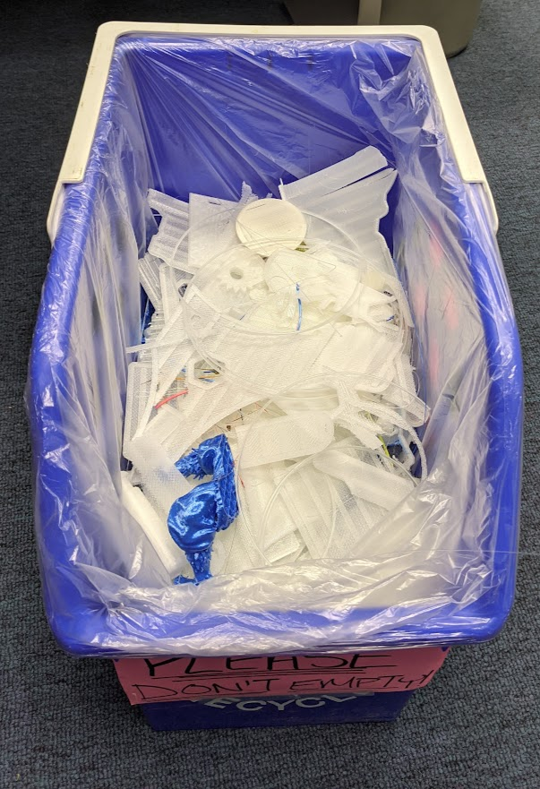 a recycling bin halfway full of PLA scraps, strands, and broken prints